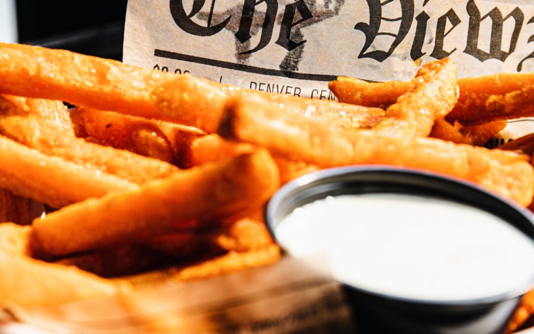 a bowl of chips in newspaper with horseradish sauce in a pot